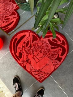 two red heart shaped rugs sitting on top of a tiled floor next to plants