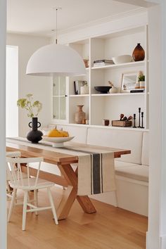 a dining room table with white chairs and a black vase sitting on top of it