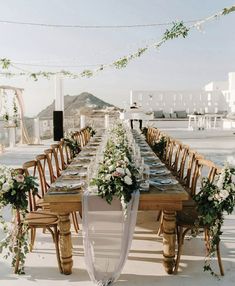 a long table set up with flowers and greenery