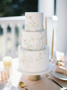 a white wedding cake sitting on top of a table next to plates and utensils