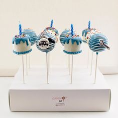 cake pops with blue frosting and sprinkles are on a white stand