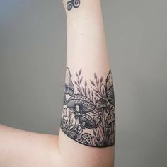 a woman's arm with a tattoo on it and an image of mushrooms in the grass