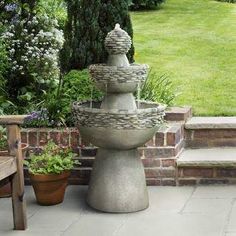 a stone fountain sitting next to a wooden bench