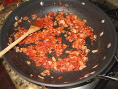 the food is being cooked in the skillet on the stove with a wooden spoon