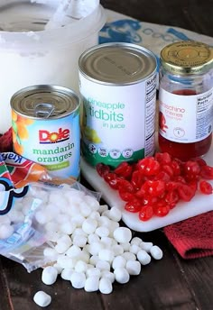 the ingredients needed to make an ice cream dessert are displayed on a wooden surface, including marshmallows and jelly beans