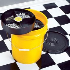 a yellow trash can sitting on top of a black and white checkered floor