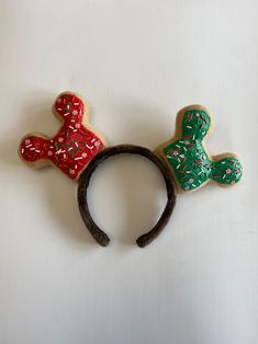 two decorated cookies are on top of a wooden headband, one is green and the other is red