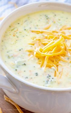 a white bowl filled with cheese soup on top of a cutting board next to crackers