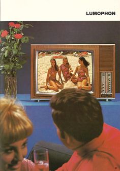 two women and a man sitting in front of a television