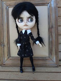 a doll with long black hair wearing a dress