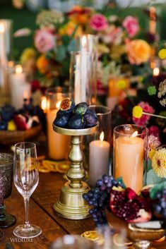 the table is set with candles, fruit and flowers