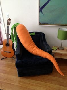 a carrot sitting on top of a chair next to a guitar