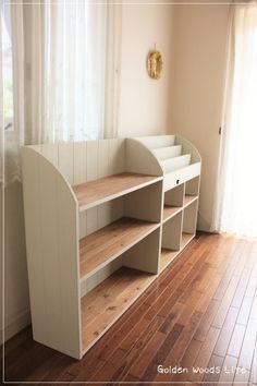 an empty room with wooden floors and white shelves on the wall next to a window