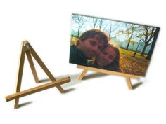 two people are posing for a picture in front of a wooden easel with a photo on it