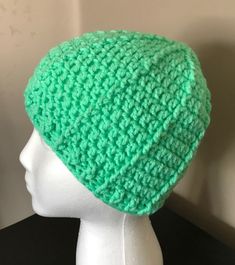 a white mannequin head wearing a green crochet hat