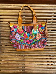 A stunning happy and unique piece that will add charm and beauty to any traveling . Leather and a beautiful handmade Huipil Weaved on a backstrap loom, it takes more than six months to complete one and is a unique piece that will add color and style to any wardrobe , A huipil is a women's blouse worn by Mayan women from Guatemala. Each handmade Huipil its unique since it depends on the inspiration of the weaver. Size inches wide 19 X tall 14 inches wide 6 inches depth 5 metal feet at the bottom Embroidered Natural Shoulder Bag For Travel, Handmade Multicolor Embroidery Shoulder Bag For Travel, Multicolor Hand Tooled Travel Bags, Bohemian Leather Shoulder Bag For Vacation, Leather Bohemian Shoulder Bag For Vacation, Handmade Multicolor Embroidered Shoulder Bag For Vacation, Huipil Pattern, Mayan Women, Backstrap Loom