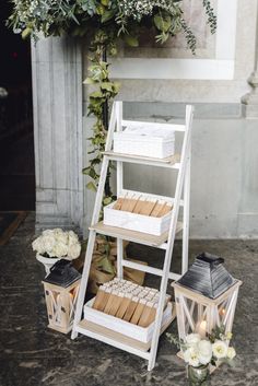 a set of three wooden shelves with candles and flowers on the floor next to them