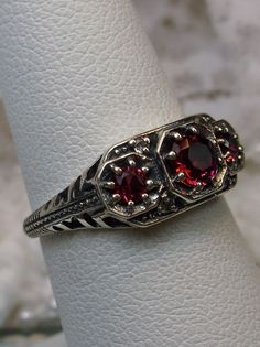 "Simulated Red Ruby Ring Description Dainty 3Stone Design#161 MADE TO ORDER This is a high-quality Edwardian reproduction filigree ring in sterling silver. This filigree 3 stone ring is set with 3 lovely simulated red ruby gemstones. The round full cut red ruby gem in the center is 4.5mm. The 2 garnets on each side are 2.5mm. The face of the ring is 15.5mm (5/8th\") east-west on the finger and 7mm (1/4th\") north-south on the finger. The inside of the band is marked 925 for sterling. Notice the Formal Red Ruby Ring With Three Stones, Formal Ruby Three Stone Ring, Formal Red Three Stone Ruby Ring, Formal Red Three Stone Rings, Red Ruby Three Stone Wedding Ring, Red Three Stone Ruby Ring For Wedding, Vintage Red Ruby Ring With Intricate Design, Art Deco Red Ruby Ring For Formal Occasions, Red Art Deco Ruby Ring For Formal Occasions