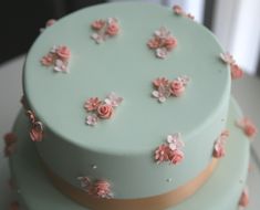 there is a three layer cake with pink flowers on the top and blue frosting