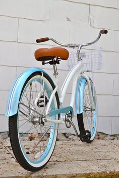 a blue and white bicycle parked in front of a brick building with a brown seat