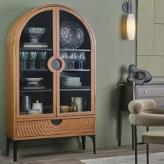 a wooden cabinet with glass doors and dishes on it's shelves in a living room