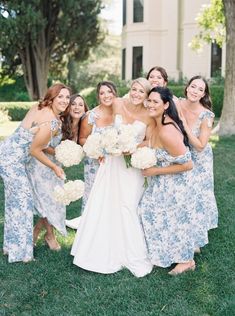 a group of women standing next to each other in front of a building with white flowers