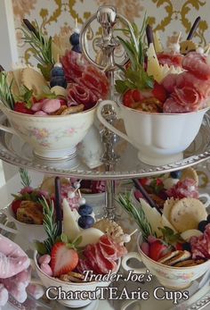 three tiered tray with bowls and cups filled with fruit, meats and veggies