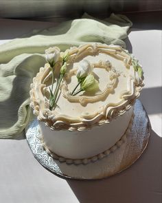 a cake with white frosting and flowers sitting on top of a silver platter