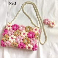 a pink and white purse sitting on top of a bed next to two small beads