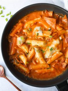 a skillet filled with pasta and sauce on top of a white table next to garlic