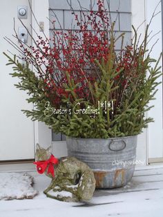 a potted plant with red berries in it and a cat figurine sitting next to it