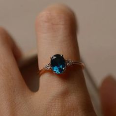 a woman's hand with a ring on it and a blue stone in the middle