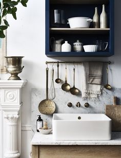 a white sink sitting under a shelf filled with pots and pans on top of a counter