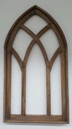 an arched wooden window mounted to the side of a wall