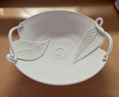 a white bowl with two leaves on it