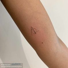 a person's arm with a small triangle tattoo on the left side of their arm