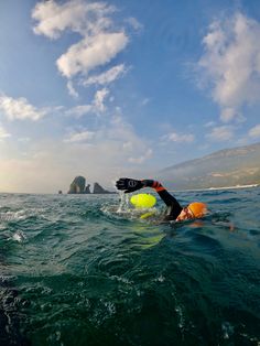 a person swimming in the ocean with a yellow and black ball on their back end