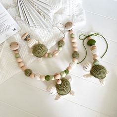 two necklaces made out of wooden beads on a white table next to an open book