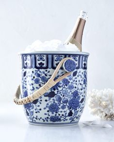 a blue and white flowered bucket with a bottle of champagne in it next to cotton swabs