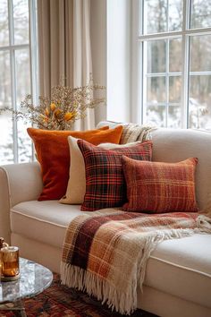 a living room filled with lots of pillows and blankets on top of a white couch