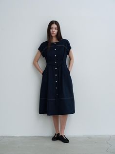 This product, a Boat Neck Long Dress in navy, combines understated elegance with practical design elements. It features short sleeves and a structured waist tie to accentuate the silhouette, while the full-length button placket ensures easy wearability. Strategic stitching along the seams creates a subtle contouring effect, enhancing the overall look of the dress. - This Boat Neck Long Dress features a buttoned front from top to bottom for ease of dressing and versatility in style.- Includes a waist tie that can be adjusted to fit comfortably while emphasizing the wearer's shape.- Designed with short sleeves and a boat neckline which offer a balanced look that is both modest and stylish.- Utilizes contrasting stitching to outline the dress, adding depth and visual interest to its stra Modern Short Sleeve Midi Dress For Work, Modern Short Sleeve Midi Dress For Office, Navy Knee-length Midi Dress For Work, Navy Midi Dress For Spring Workwear, Classic Navy Dress For Workwear, Navy Short Sleeve Classic Dress, Navy Classic Short Sleeve Dress, Elegant Navy Short Sleeve Midi Dress, Elegant Navy Midi Dress With Buttons