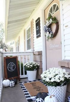 front porch decorated for fall with white pumpkins and black and white striped pots filled with flowers