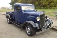 an old blue truck is parked on the street