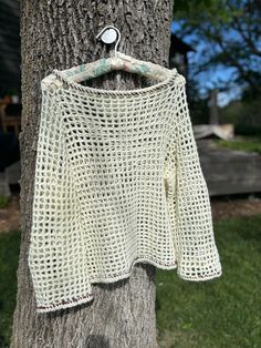 a crocheted sweater hanging on a tree