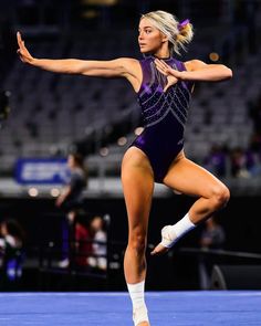 a woman in a purple leotard and white socks is doing a dance move