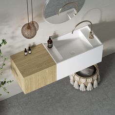 a white sink sitting under a mirror next to a wooden cabinet and potted plant