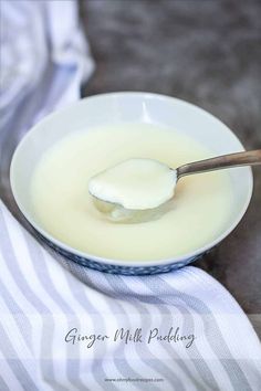 a spoon full of milk sitting on top of a white plate with a striped cloth