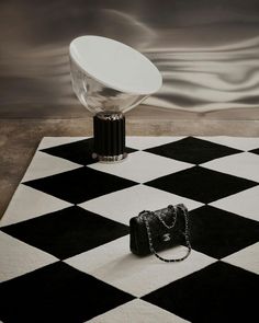 a black and white checkered rug with a handbag on it next to a lamp