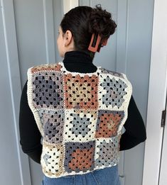 a woman standing in front of a door wearing a crocheted vest