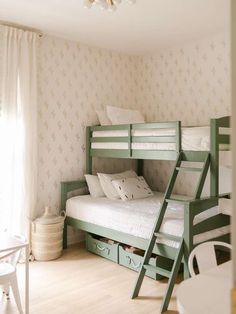 a bunk bed sitting next to a window in a room with white walls and wooden floors